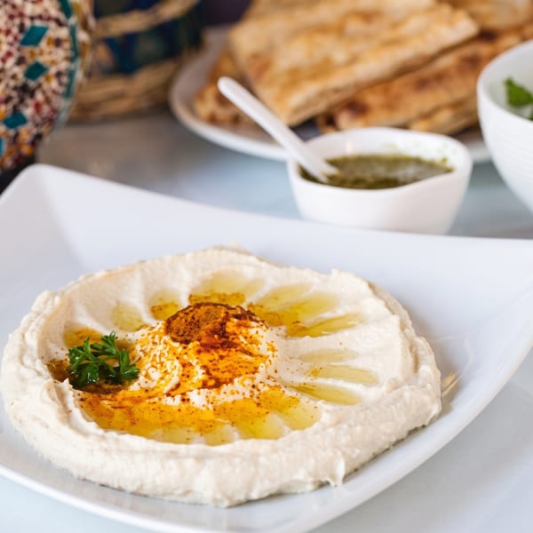 Creamy hummus drizzled with olive oil, paprika, and parsley, served with pita bread.